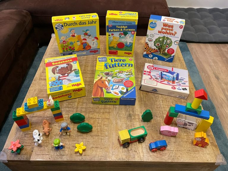 Kindertagespflege Rodenbach - Spielspaß Bunte Lernspielzeuge und Spiele auf einem Tisch, darunter Bauklötze und Puzzle.