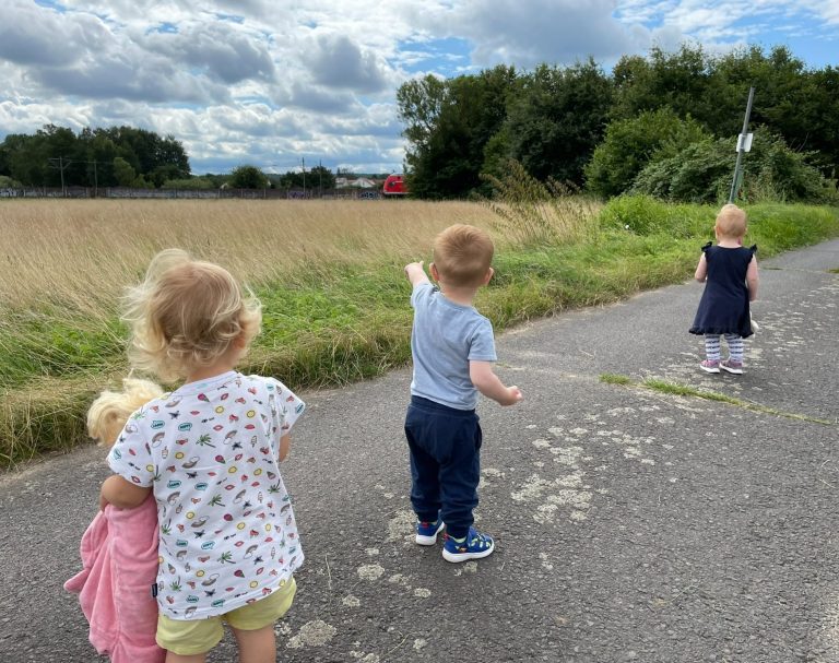 Farbenzwerge auf Endeckungstour - Kindertagespflege Rodenbach Drei kleine Kinder stehen auf einem Weg und schauen auf ein Feld.
